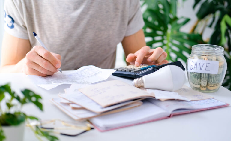 A man counts a bill on a calculator on the table. Payment of utility services.